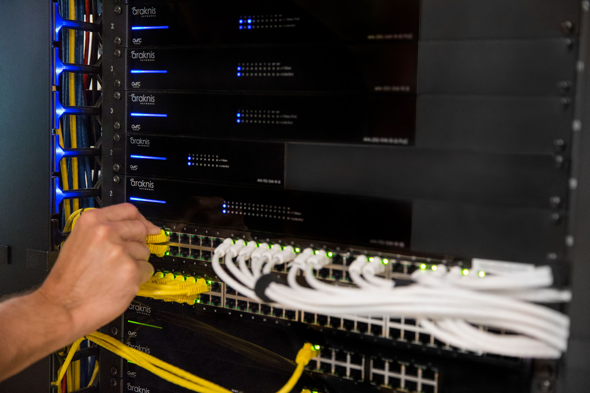Technician connecting Ethernet cables in server rack