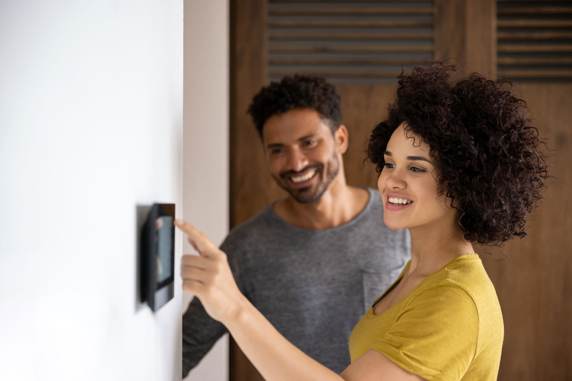 Couple adjusting smart thermostat at home