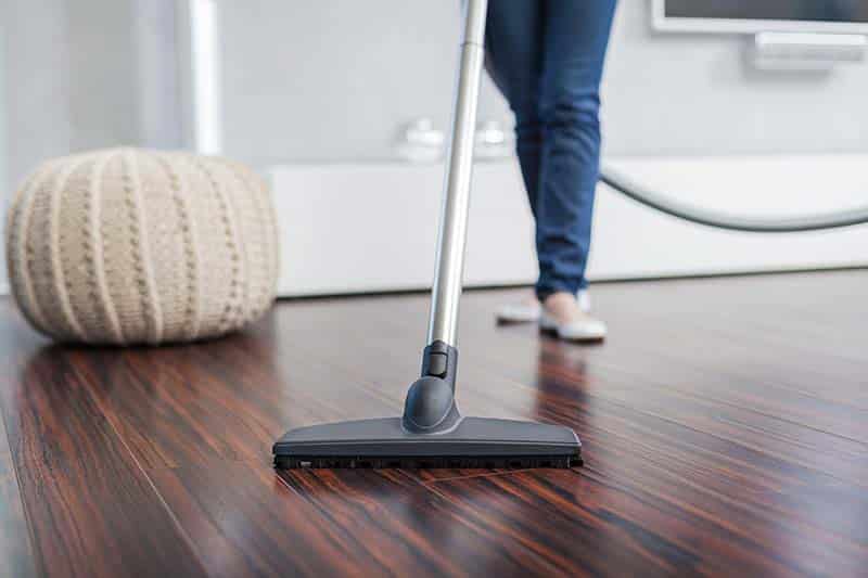 Person vacuuming clean hardwood floor at home